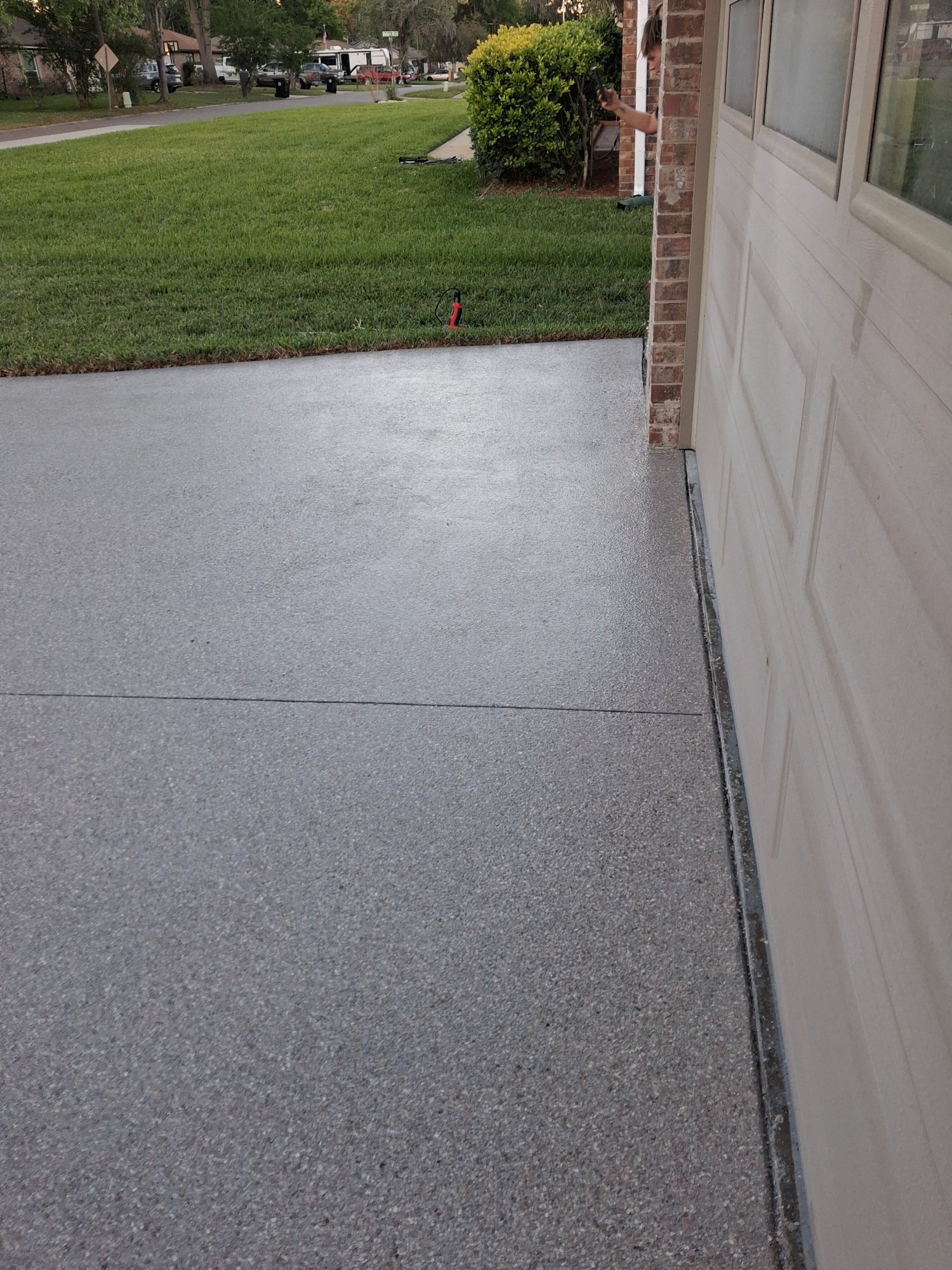 Finished grey flake driveway curving past a planter at dusk