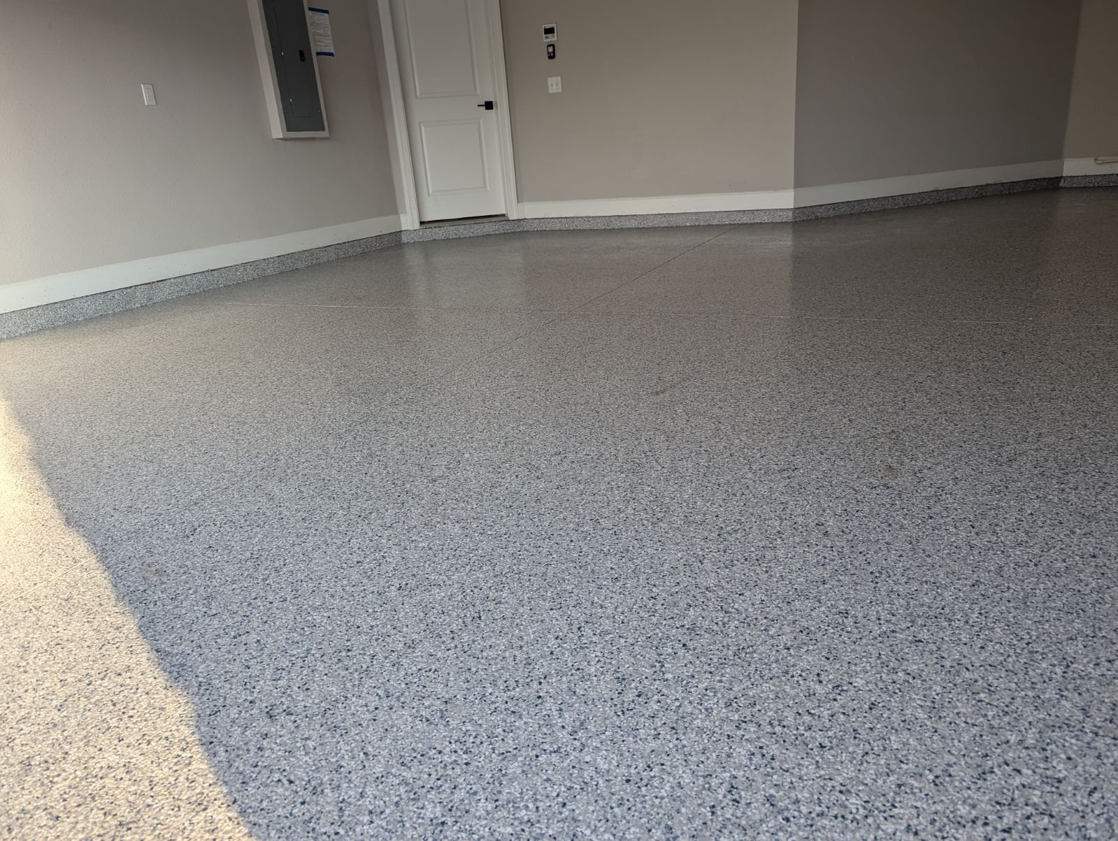 Large empty garage bay with mottled silver and black metallic floor coating